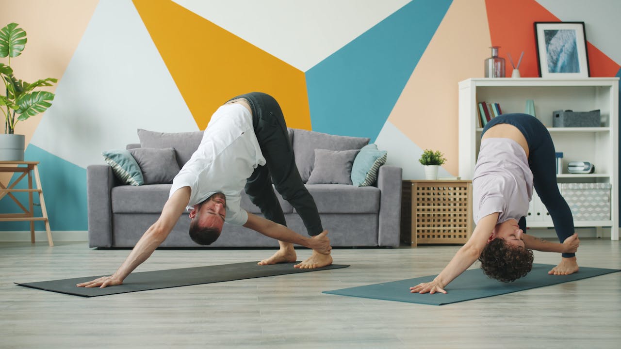 services-03 Couple practicing yoga together in a stylish indoor living room with geometric wall design.