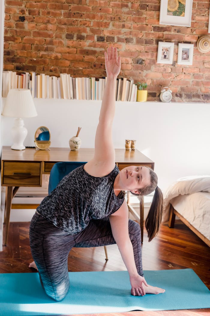 services-02 Woman practicing yoga indoors with stylish interior and brick wall backdrop.