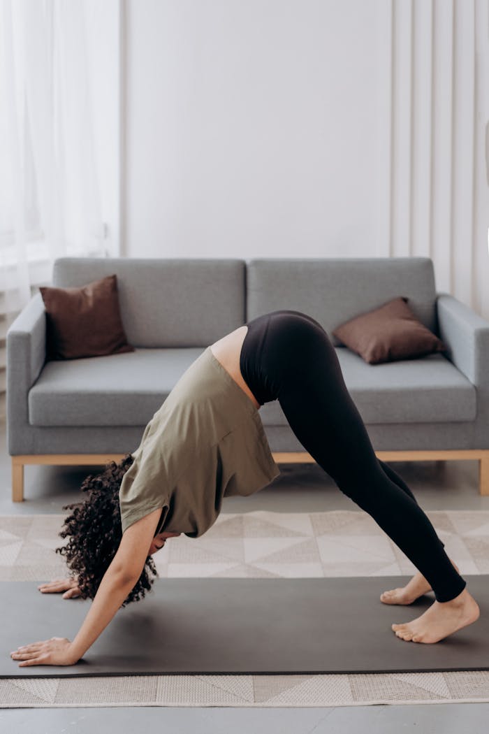 missions A young woman performing yoga pose in a modern living room setting, promoting health and relaxation.