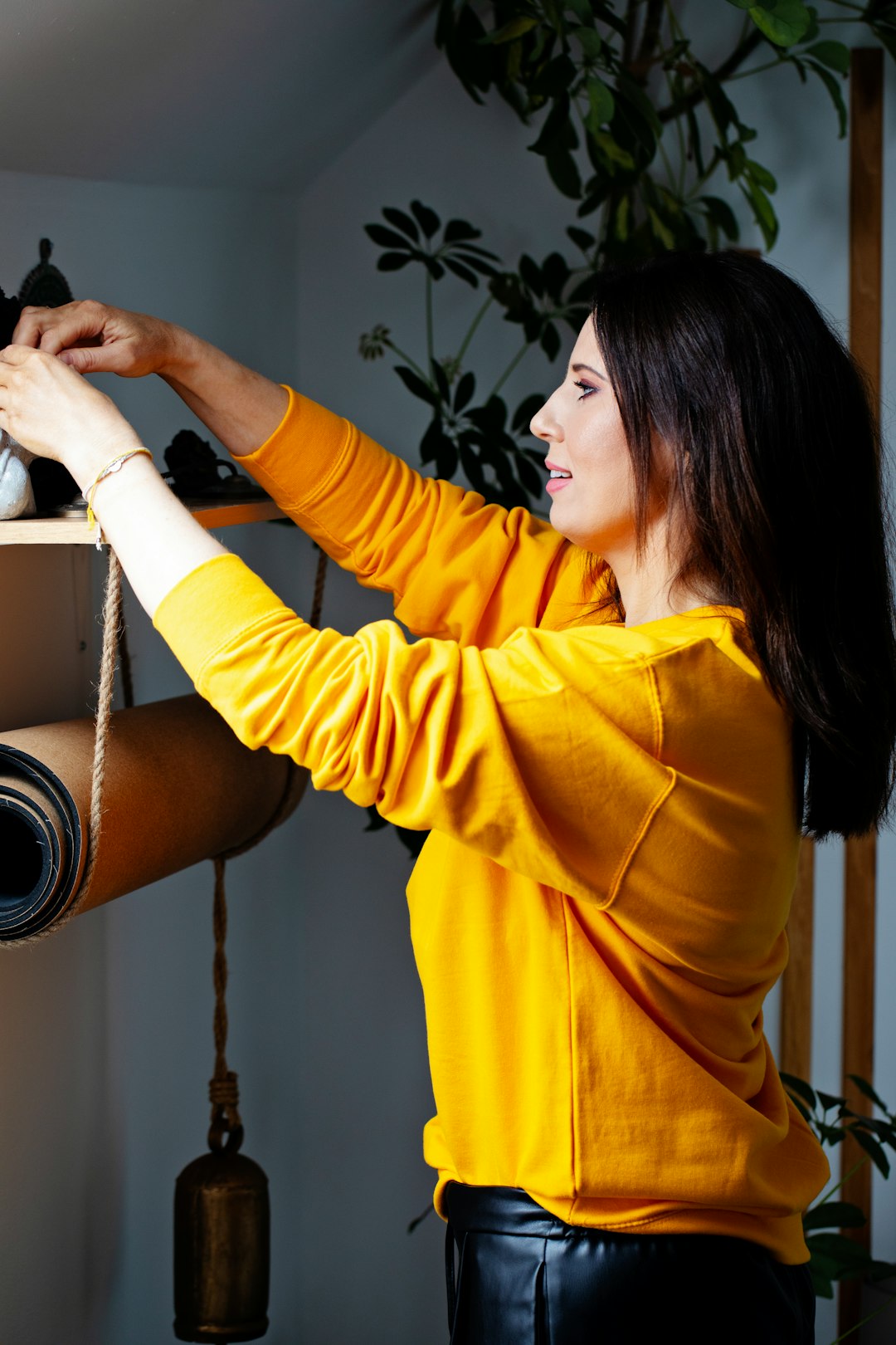 woman-in-yellow-sweater-organizing-shelf-with-plants-vstcdbu2cpe